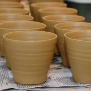 Herstellung handgetöpferter Keramik - Fertig gedrehte Keramikbecher beim Trocknen mit weiteren handgetöpferten Bechern aus Keramik im Hintergrund