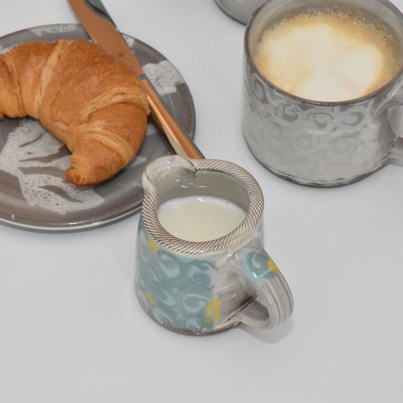 Handgetöpferte Keramik - Handgetöpfertes Sahnekännchen aus Keramik mit Teller und Tasse daneben.