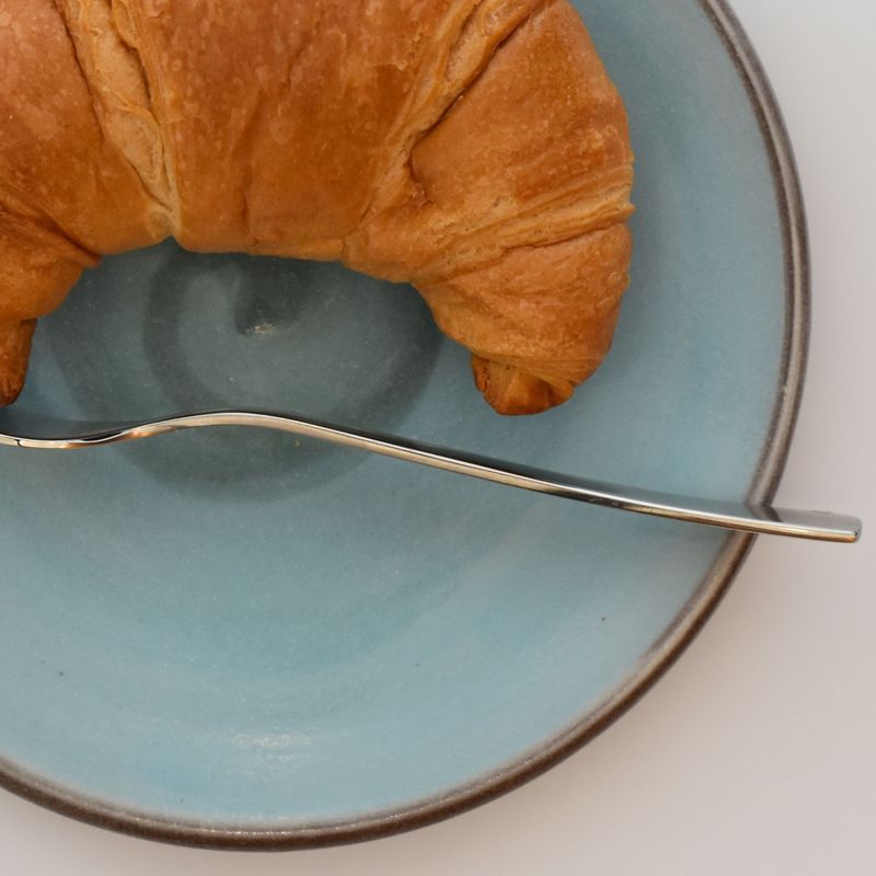 Keramikteller - Handgetöpferter Unterteller aus Keramik in blau mit einem Croissant und einer Gabel auf dem Teller.
