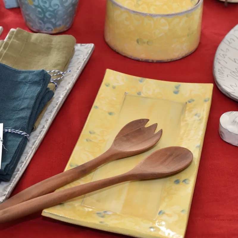 Ausstellungen & Veranstaltungen - Gelbe handgetöpferte Servierplatte aus Steinzeugkeramik mit Salatbesteck aus Holz.
